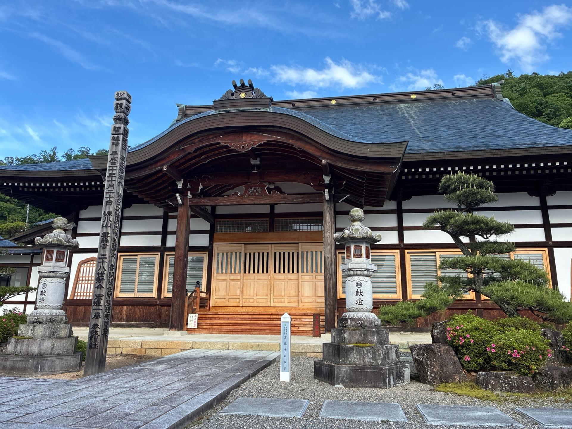 立派な瓦屋根の本堂を構えた雲龍寺。正面に石段と灯籠があり、青空が広がっている
