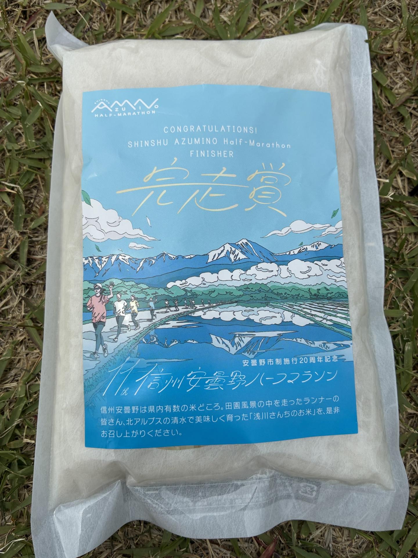 完走賞のお米の袋。北アルプスと田園風景のイラストが印刷された水色のパッケージに「完走賞」と書かれている
