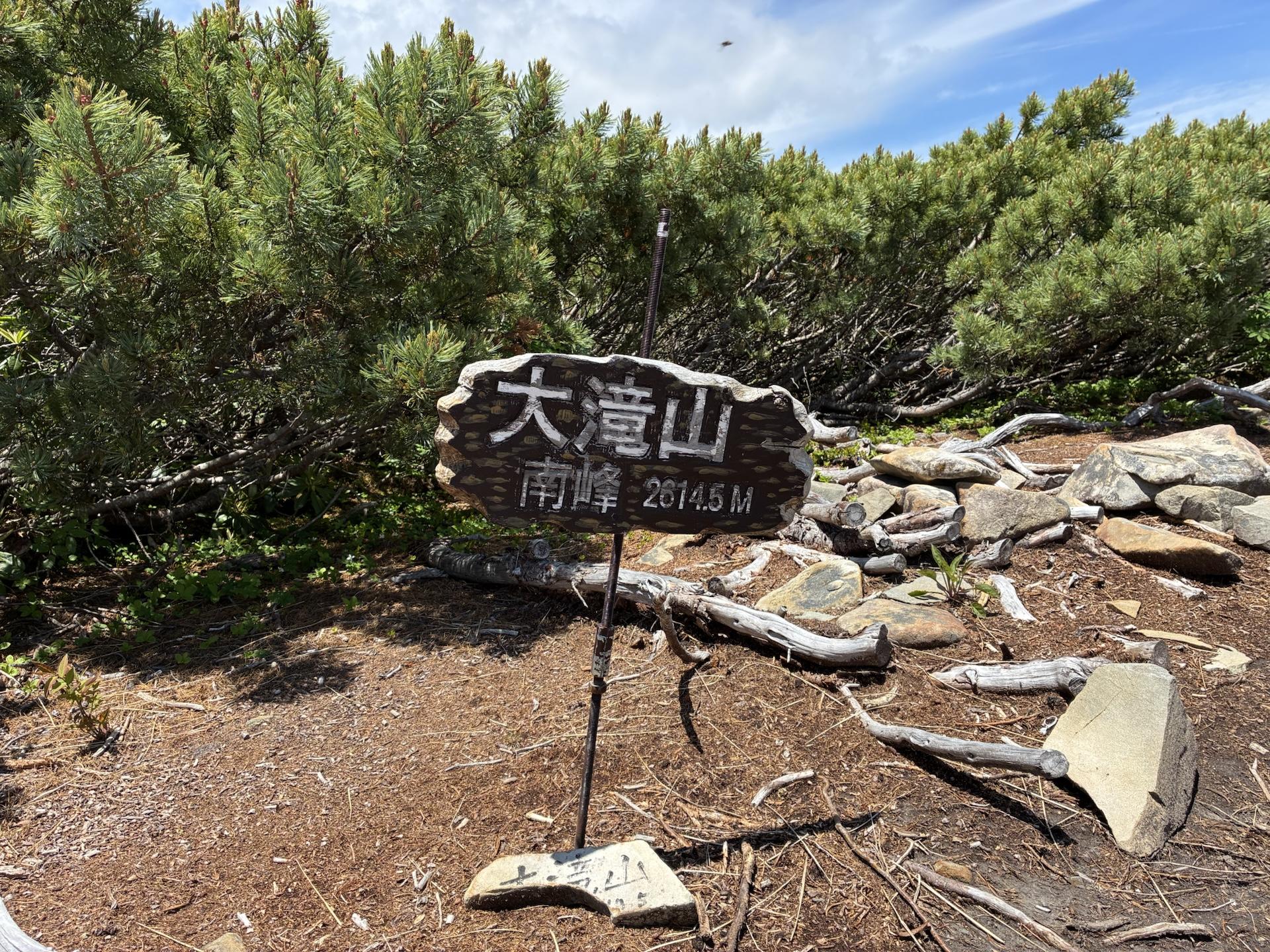 大滝山南峰の山頂。石を積んだ台に「大滝山 南峰 2616M」と書かれた板が立てかけられ、周囲はハイマツと砂礫