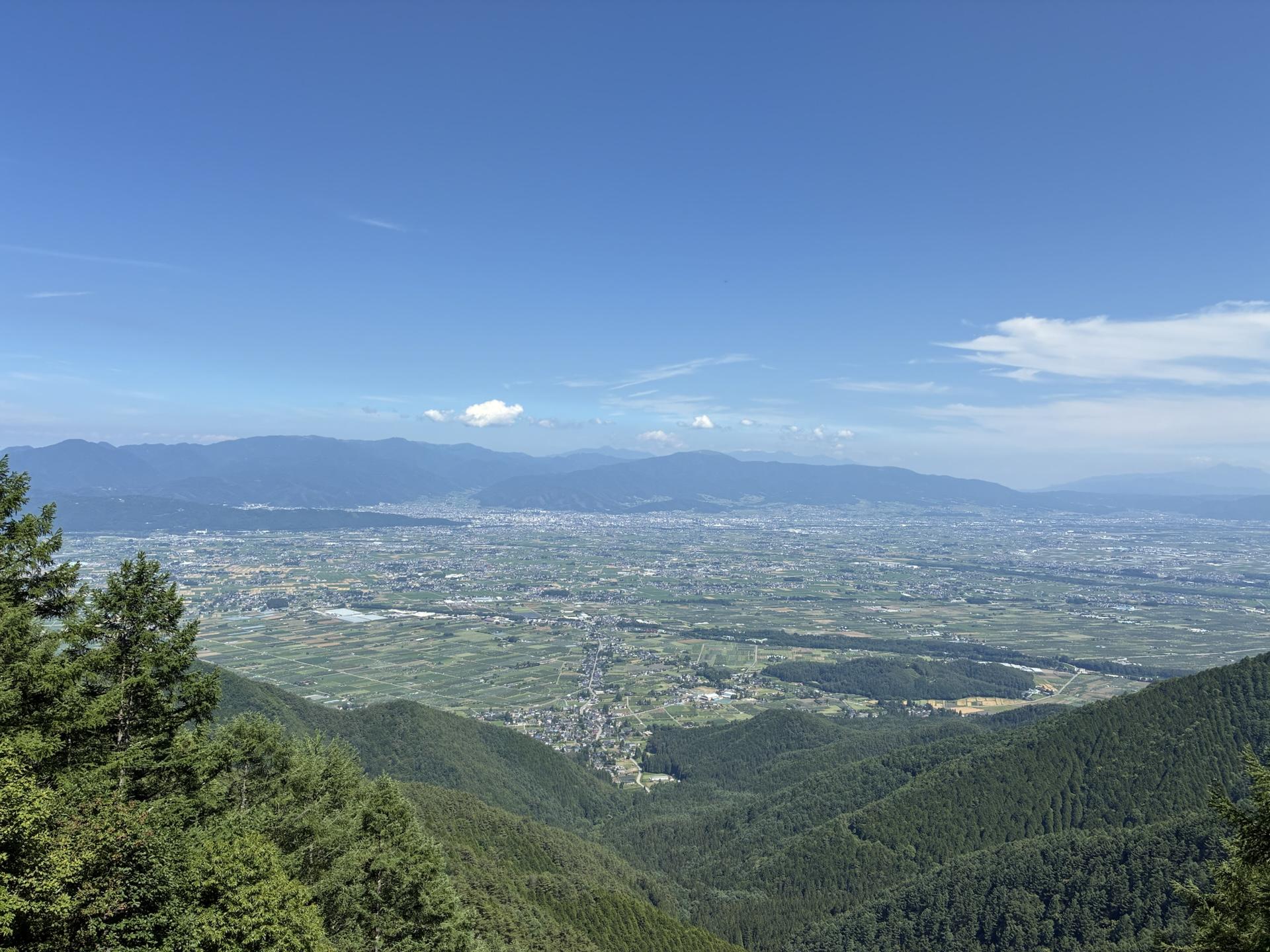 三郷スカイラインの展望台から見下ろした安曇野。眼下に緑の谷と街並みが広がり、遠くまで平野が続いている