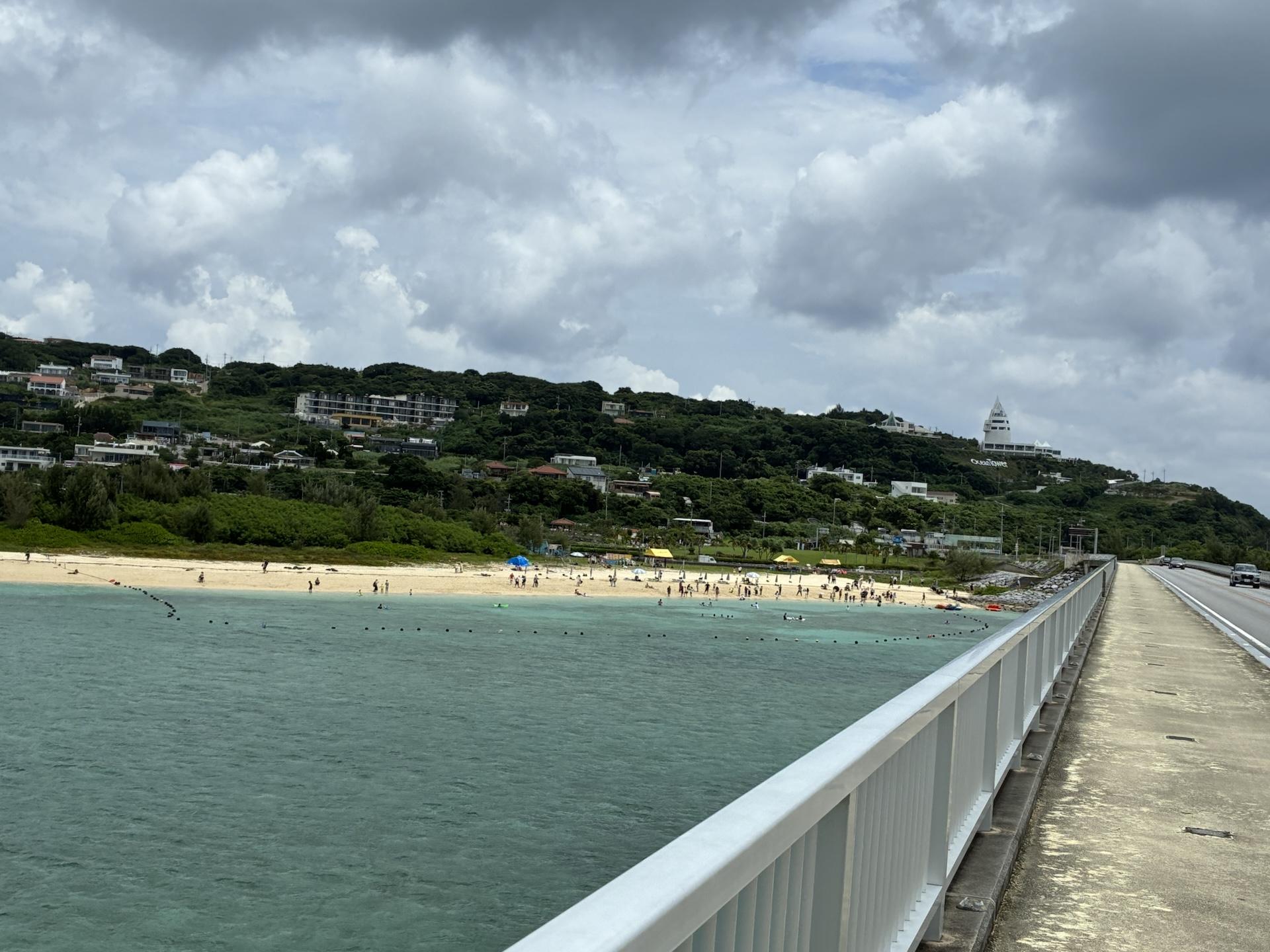 橋の上から見下ろした古宇利島のビーチ。透明度の高い浅瀬が広がり、白い砂浜に人が点在している