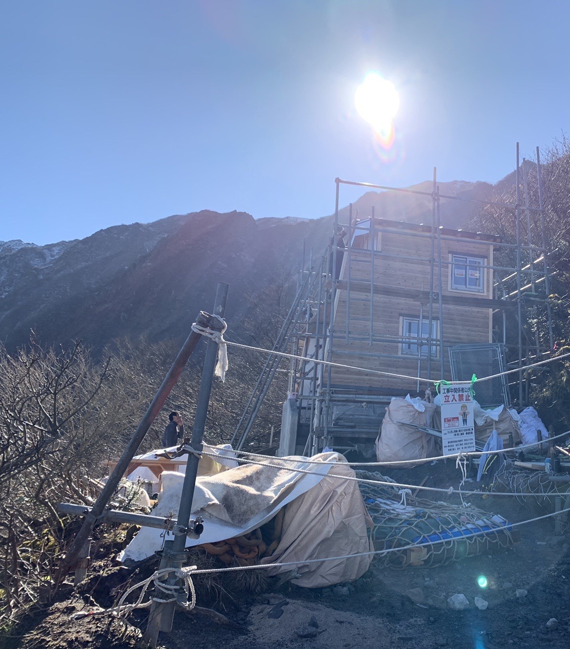 足場が組まれた工事中の建物。手前にロープが張られ、赤い字の「立入禁止」の貼り紙が下がっている