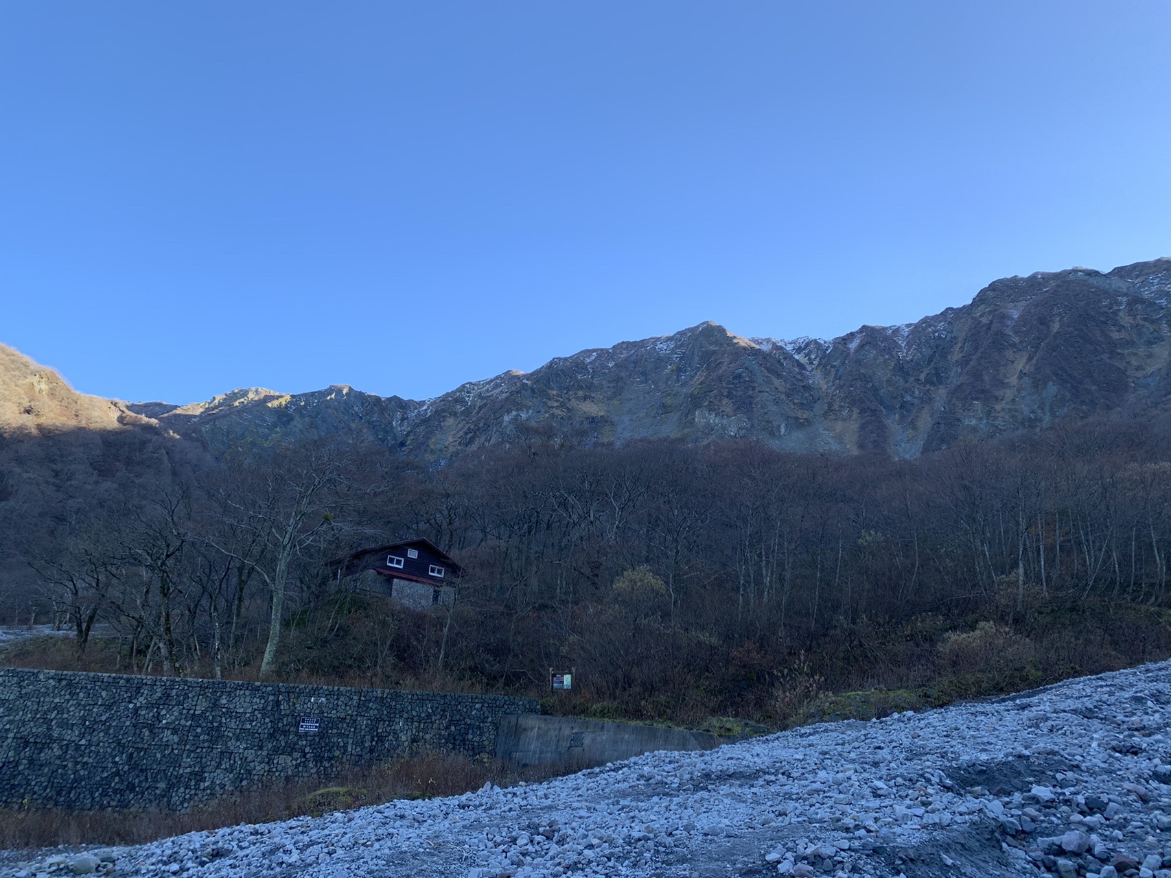 下山後に見上げた大山の岩壁。木立の向こうに崩れた岩肌の稜線がそびえ、手前は石垣と建物