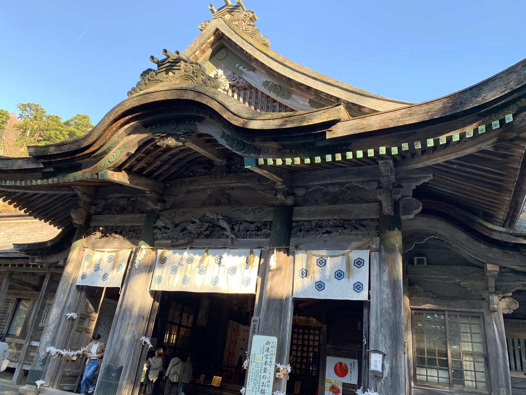 大きな木造の社殿。反り返った屋根と細かい装飾があり、正面に注連縄が張られている