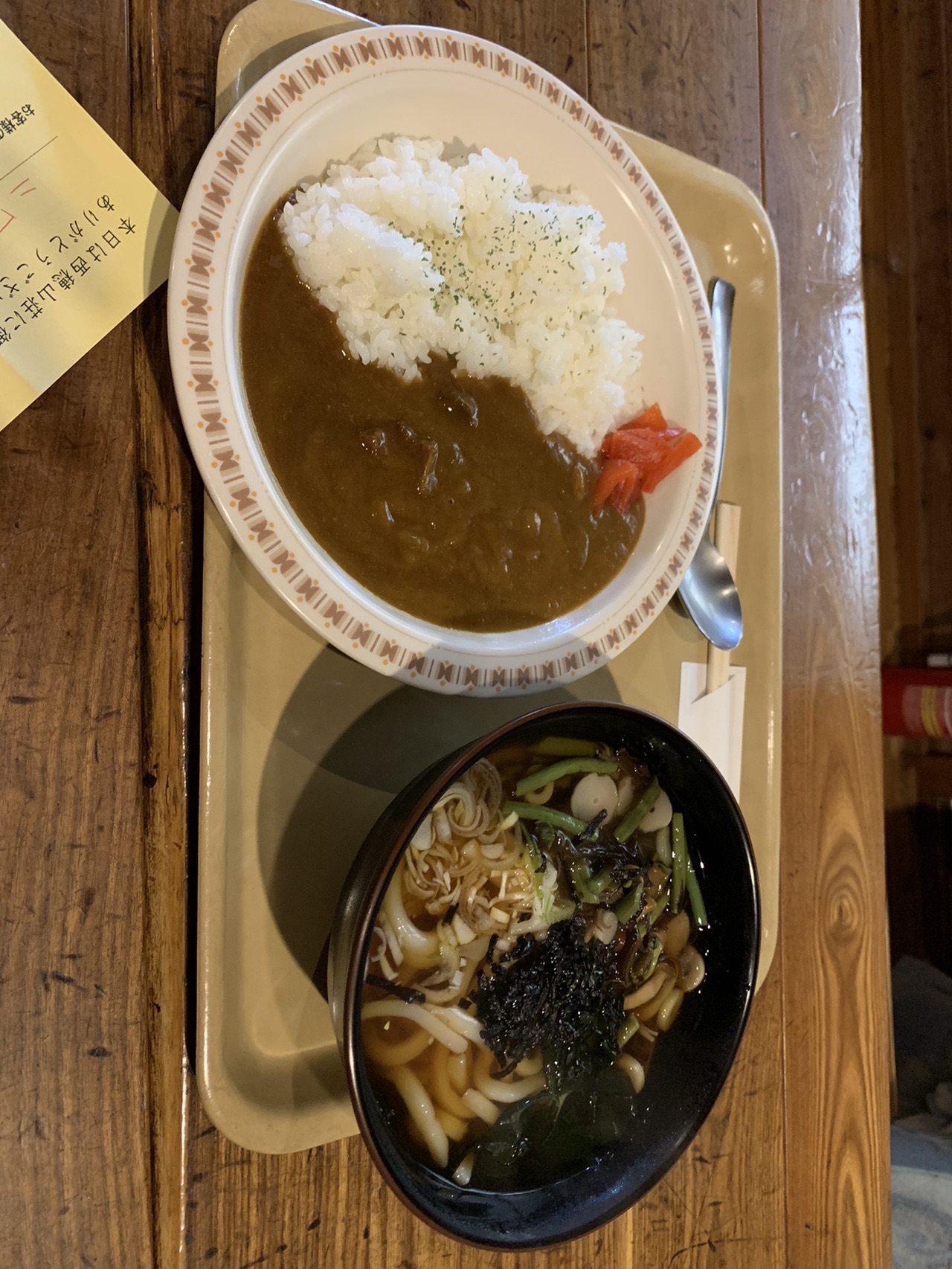 木のテーブルに置かれたカレーライスの皿と、山菜の入ったうどんの丼