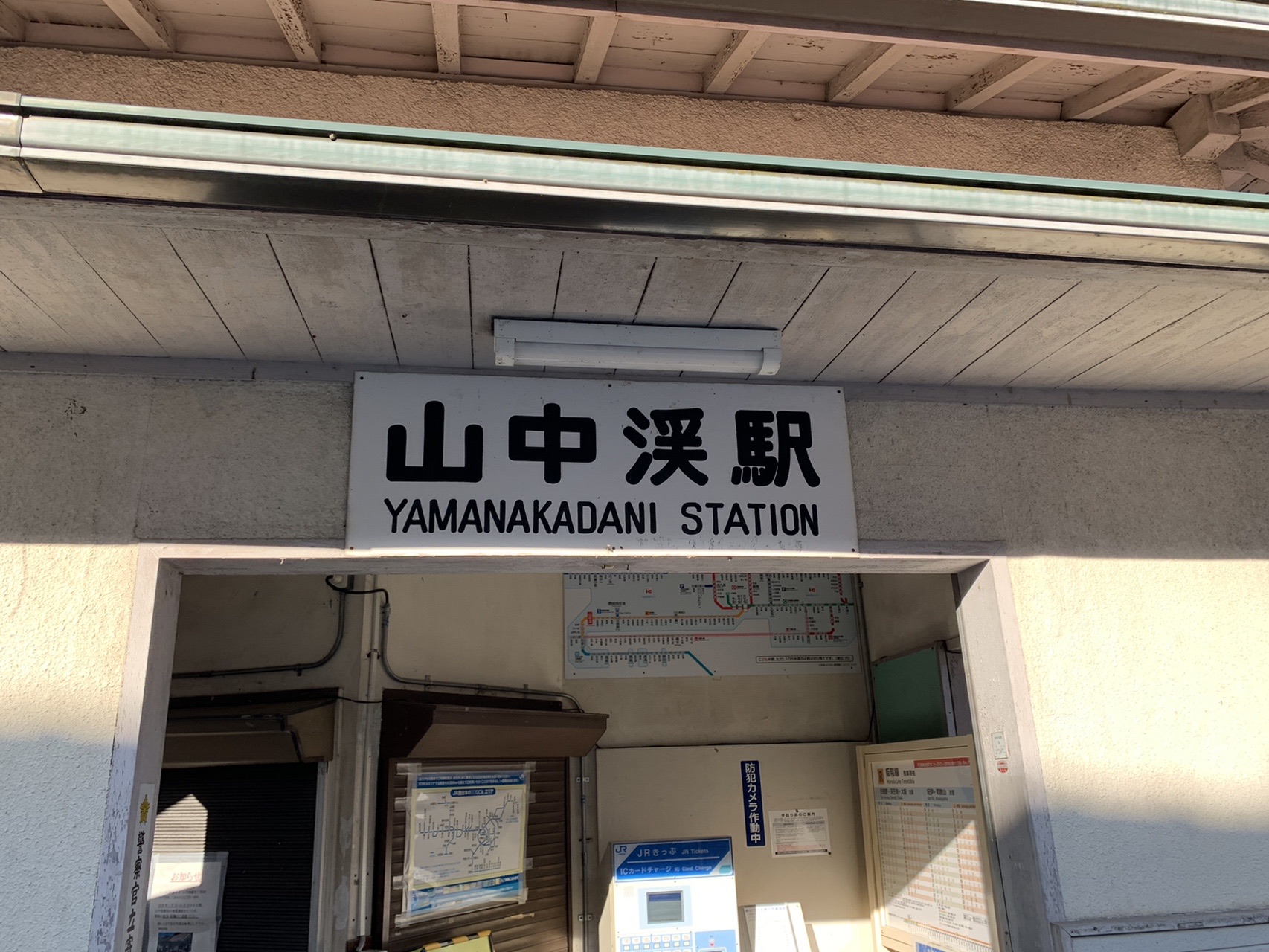 JR山中渓駅の小さな待合所。壁に「山中渓駅 YAMANAKADANI STATION」の看板が掛かっている