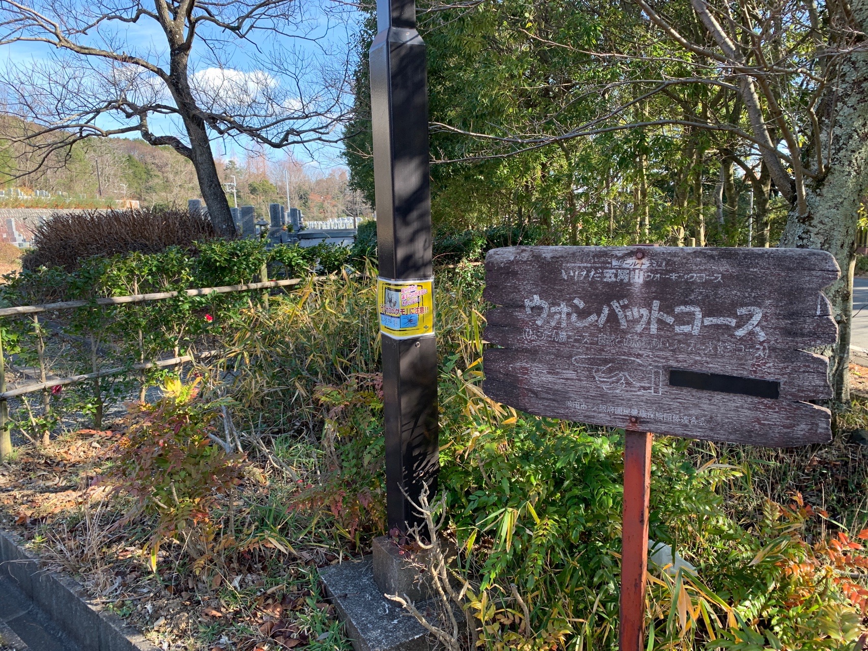 柵のそばに立つ赤い脚の看板。「ウォンバットコース」と書かれている