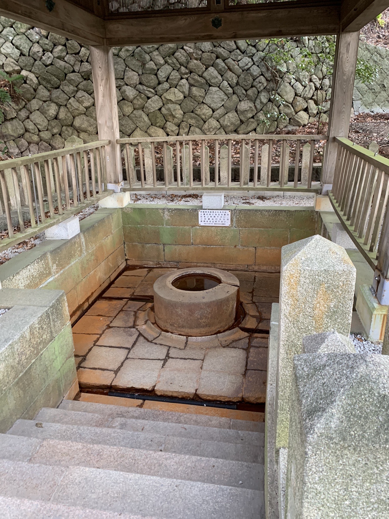 屋根のかかった石組みの空間の中央に、丸い石の井戸が据えられている