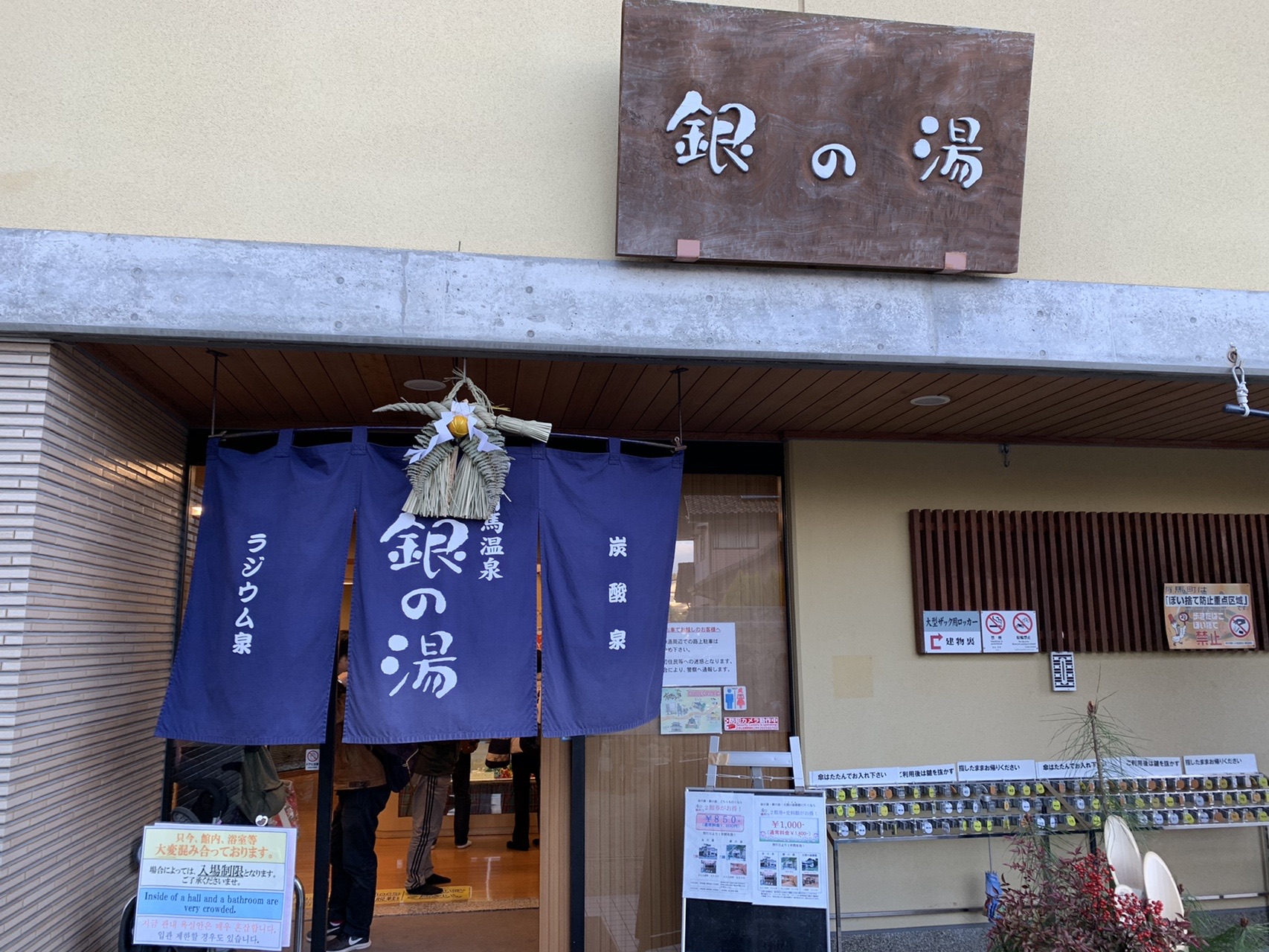 「銀の湯」と書かれた木の看板が掛かった建物の入口。紺色の暖簾が下がっている