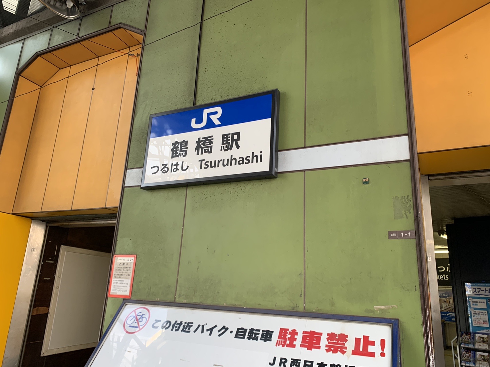 JR鶴橋駅の壁に付いた青い駅名標。「鶴橋駅 つるはし Tsuruhashi」と書かれ、下に駐輪禁止の貼り紙がある