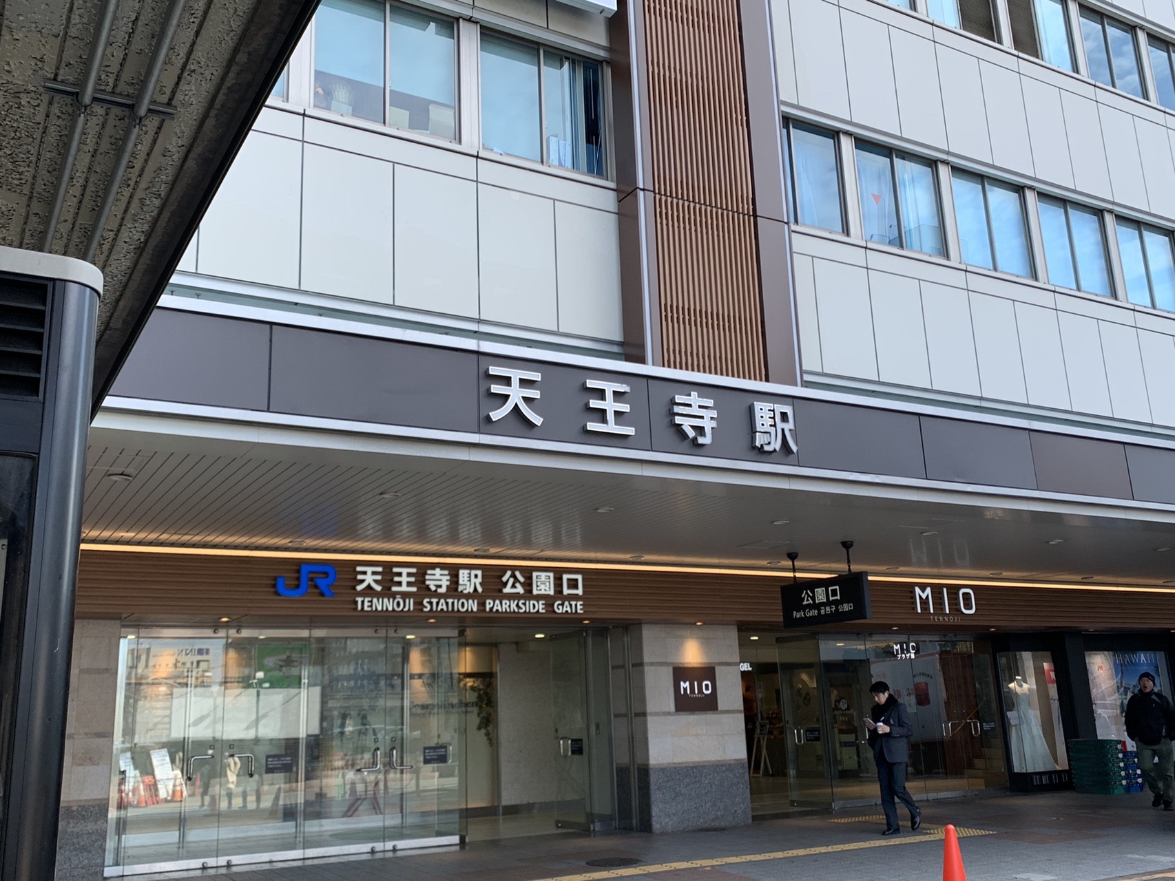 JR天王寺駅の公園口。ガラス張りの駅舎に「天王寺駅」の看板が掲げられ、人が歩いている