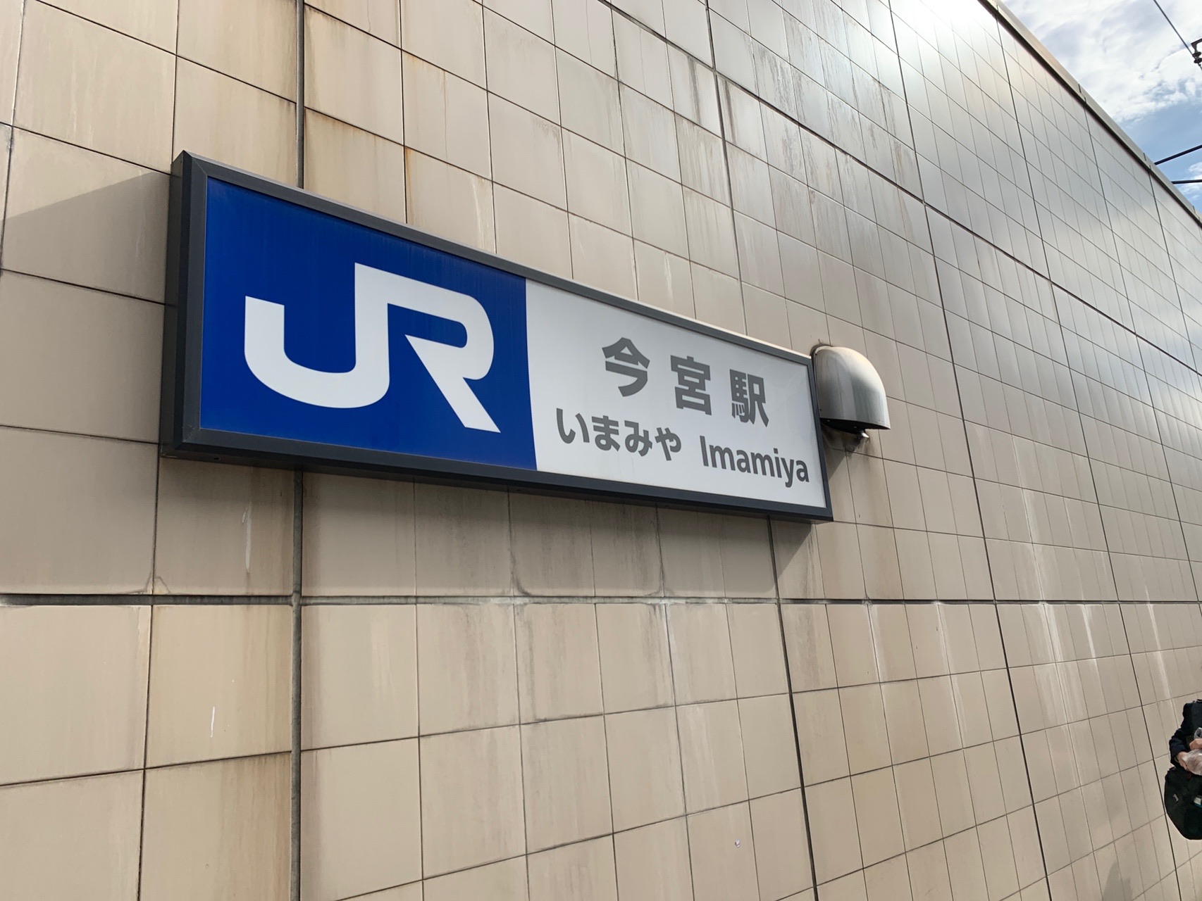 ベージュの壁面に付いたJR今宮駅の駅名標。「今宮 いまみや Imamiya」と書かれている
