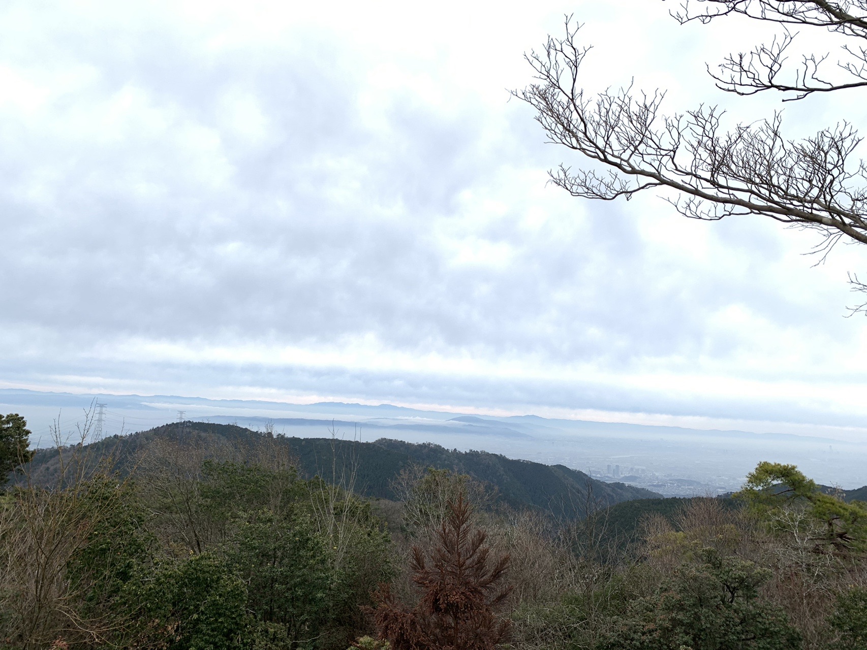山頂から見下ろす景色。手前の尾根の向こうに白い雲が敷き詰められ、街が雲の下に沈んでいる
