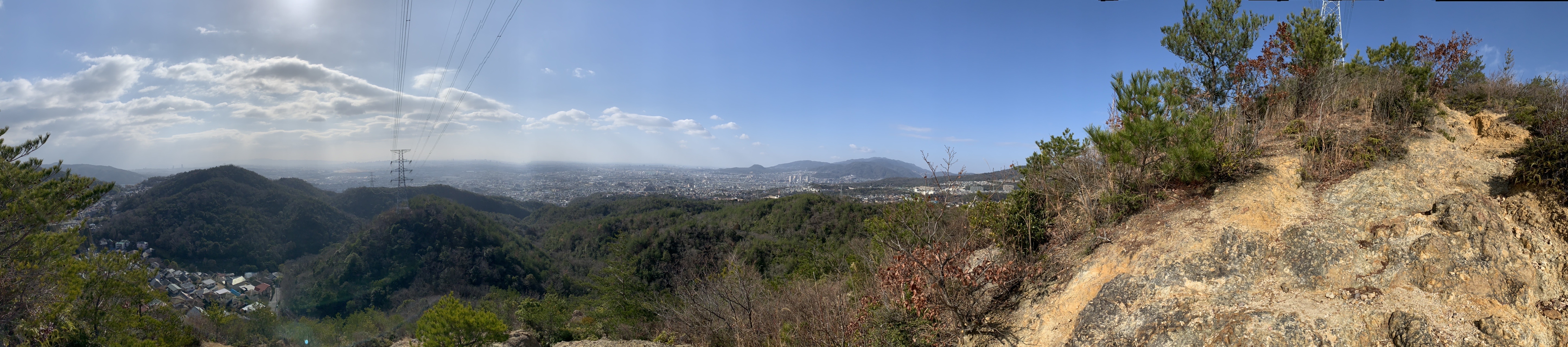 岩尾根から見渡す横長のパノラマ。手前に低い尾根が重なり、その向こうに宝塚の市街地が広がっている