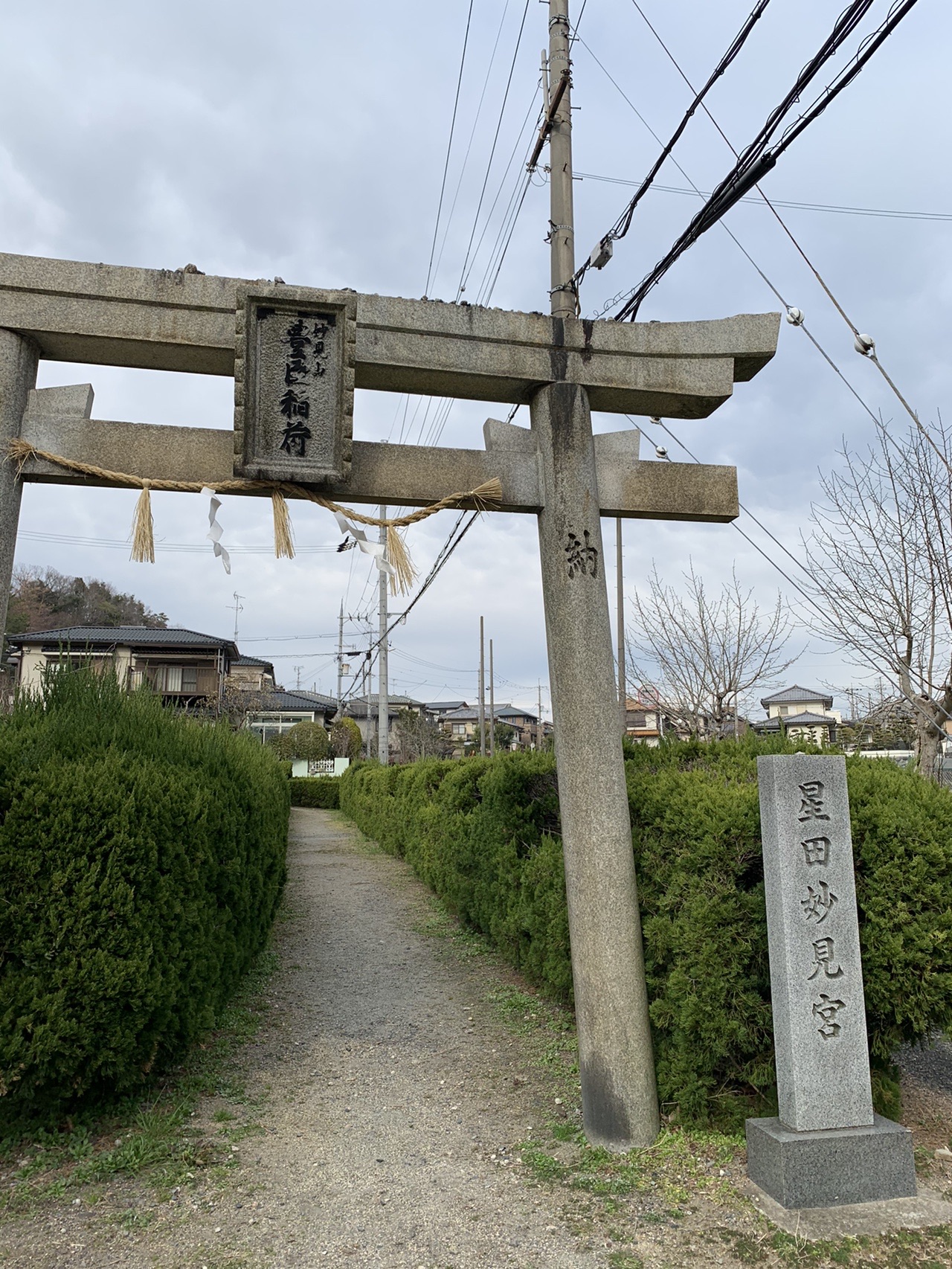 石の鳥居と「星田妙見宮」と刻まれた社標。生垣に挟まれた参道が奥へ続いている