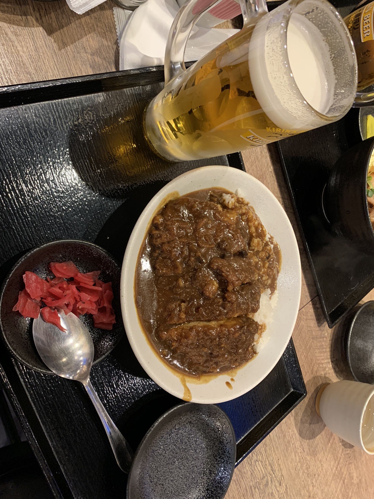 テーブルに置かれたカツカレーの皿と福神漬け、飲み物のグラス