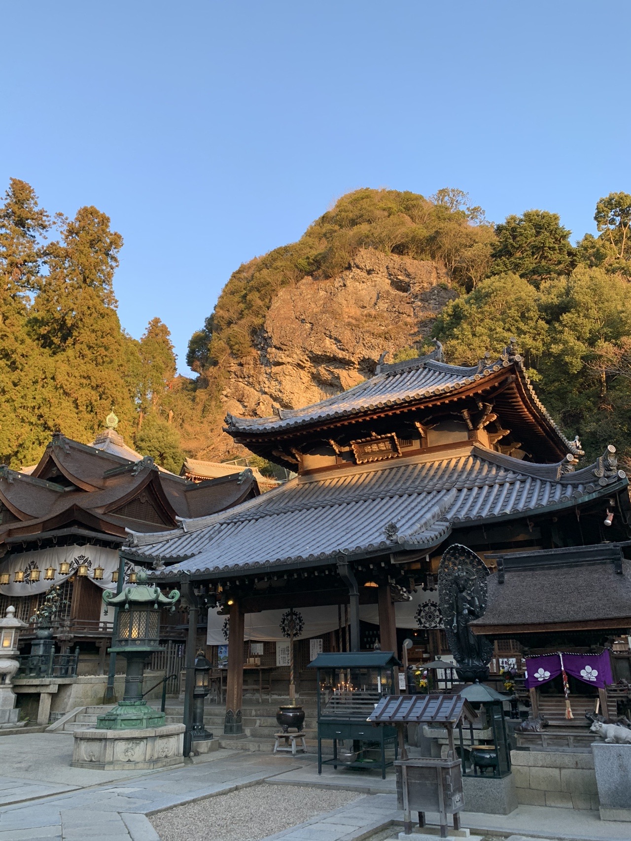 朝日を受ける宝山寺の伽藍。背後の斜面に岩肌が見えている