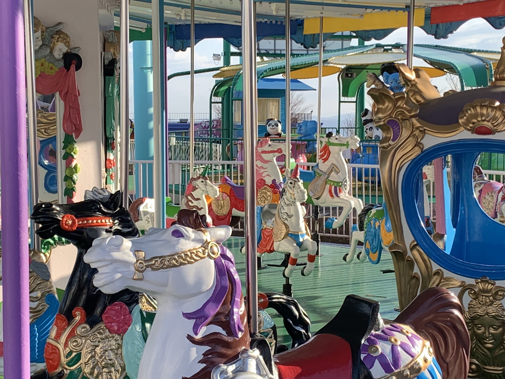 止まっているメリーゴーラウンド。白い馬が口を開けて楽しげな表情のまま静止している