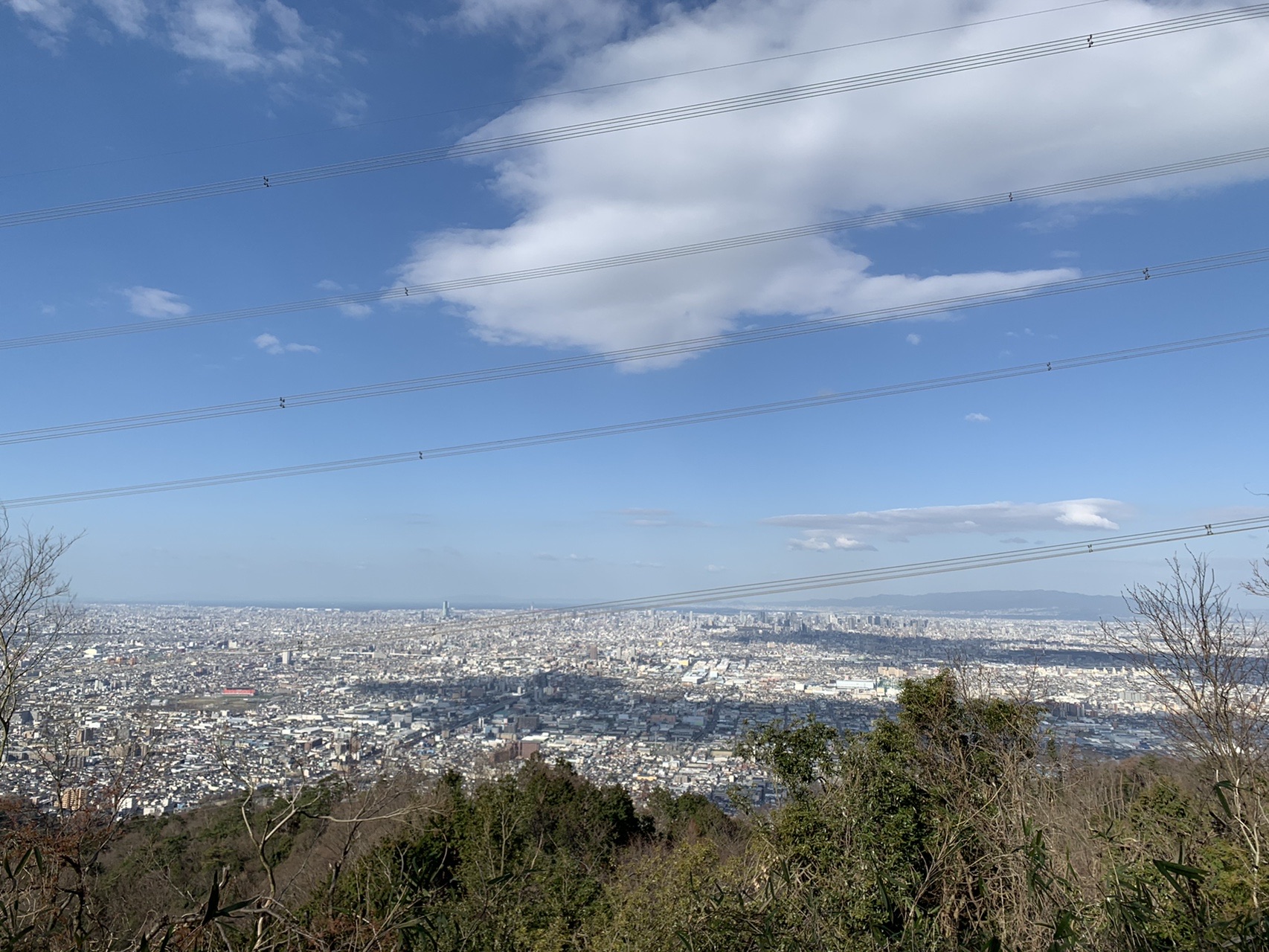 生駒山から見下ろす大阪の街。上空に雲があり、街の一部に大きな影が落ちている