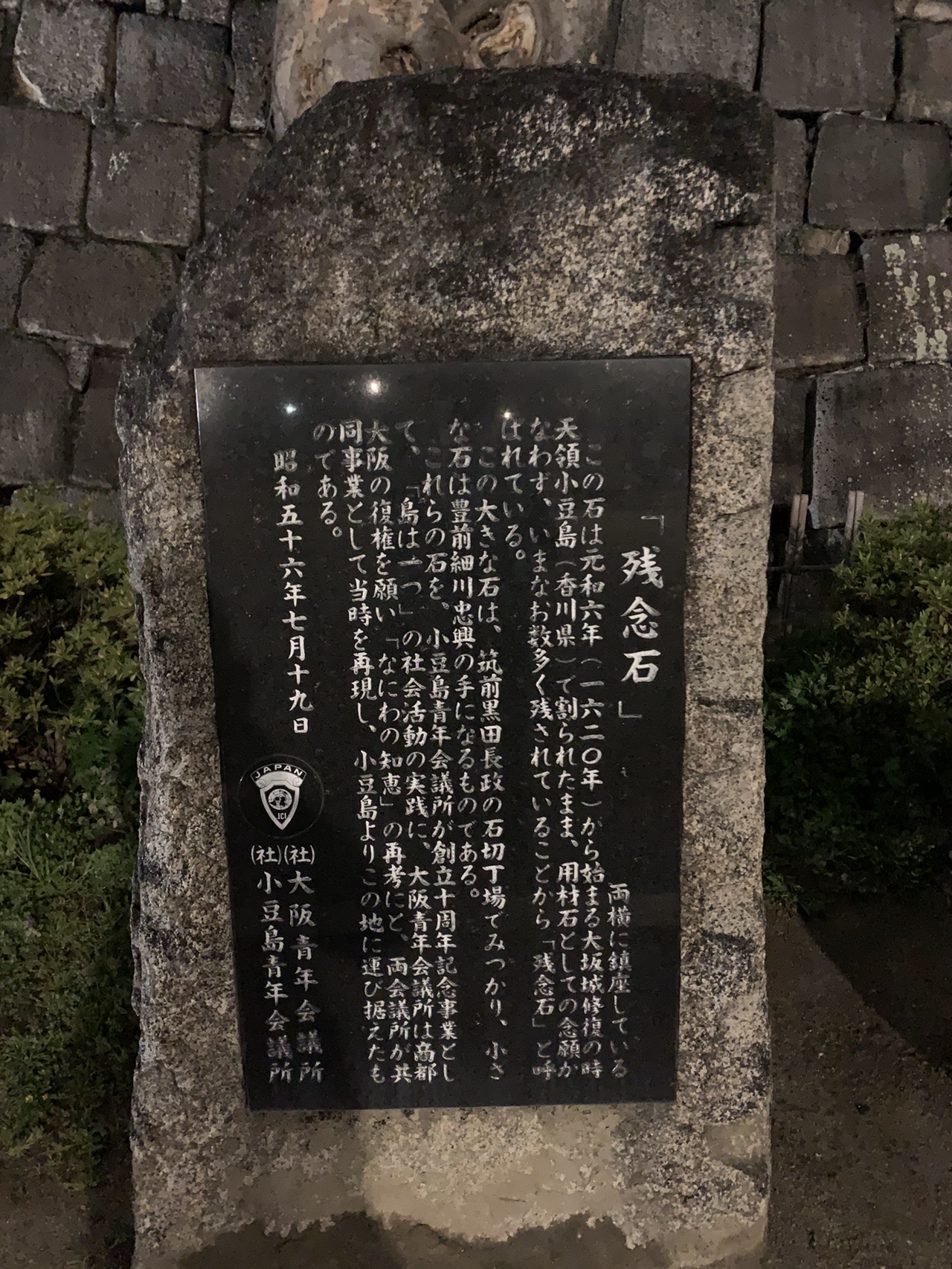 石に取り付けられた黒い説明板。「残念石」という題で由来が刻まれている
