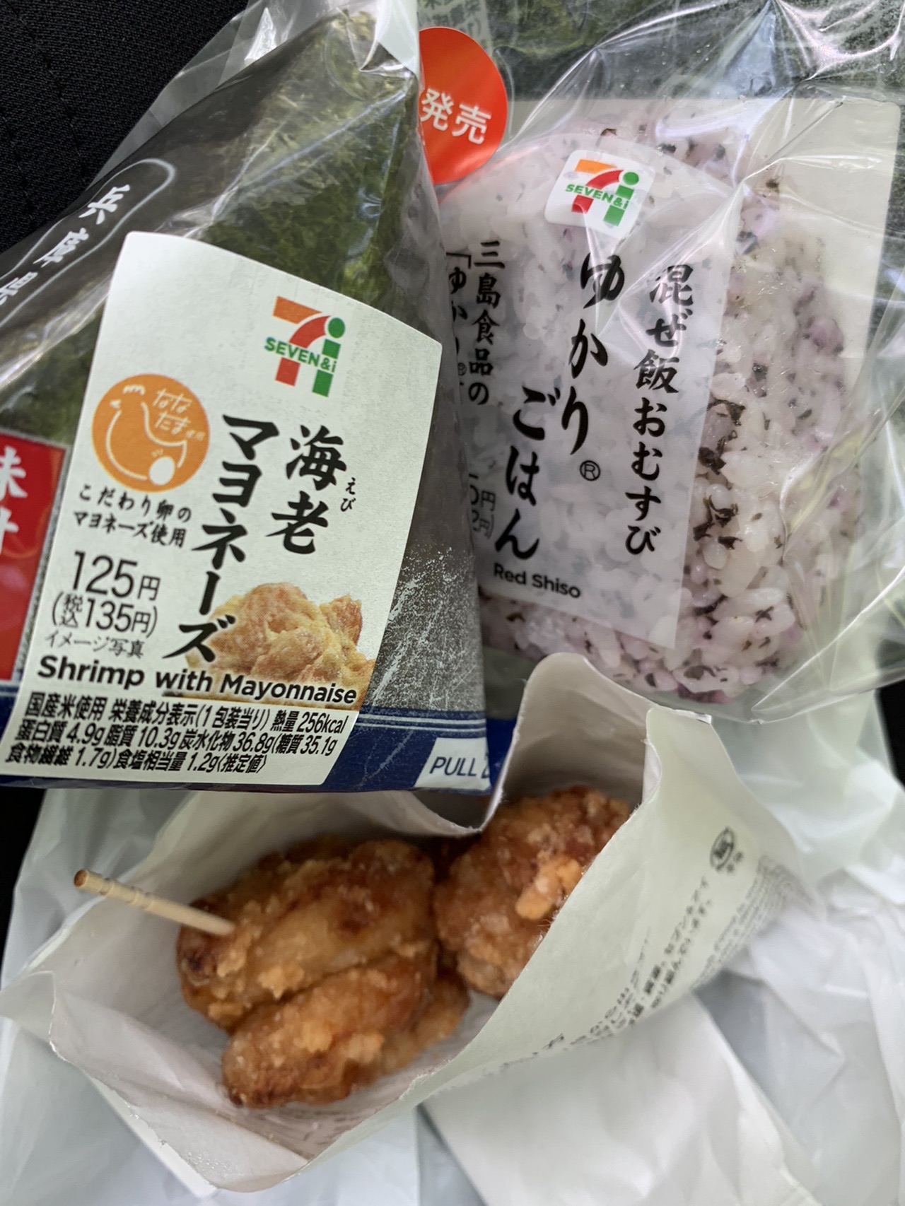 コンビニのおにぎり2個と、揚げ物の入った紙袋。ゆかりごはんと海老マヨネーズ
