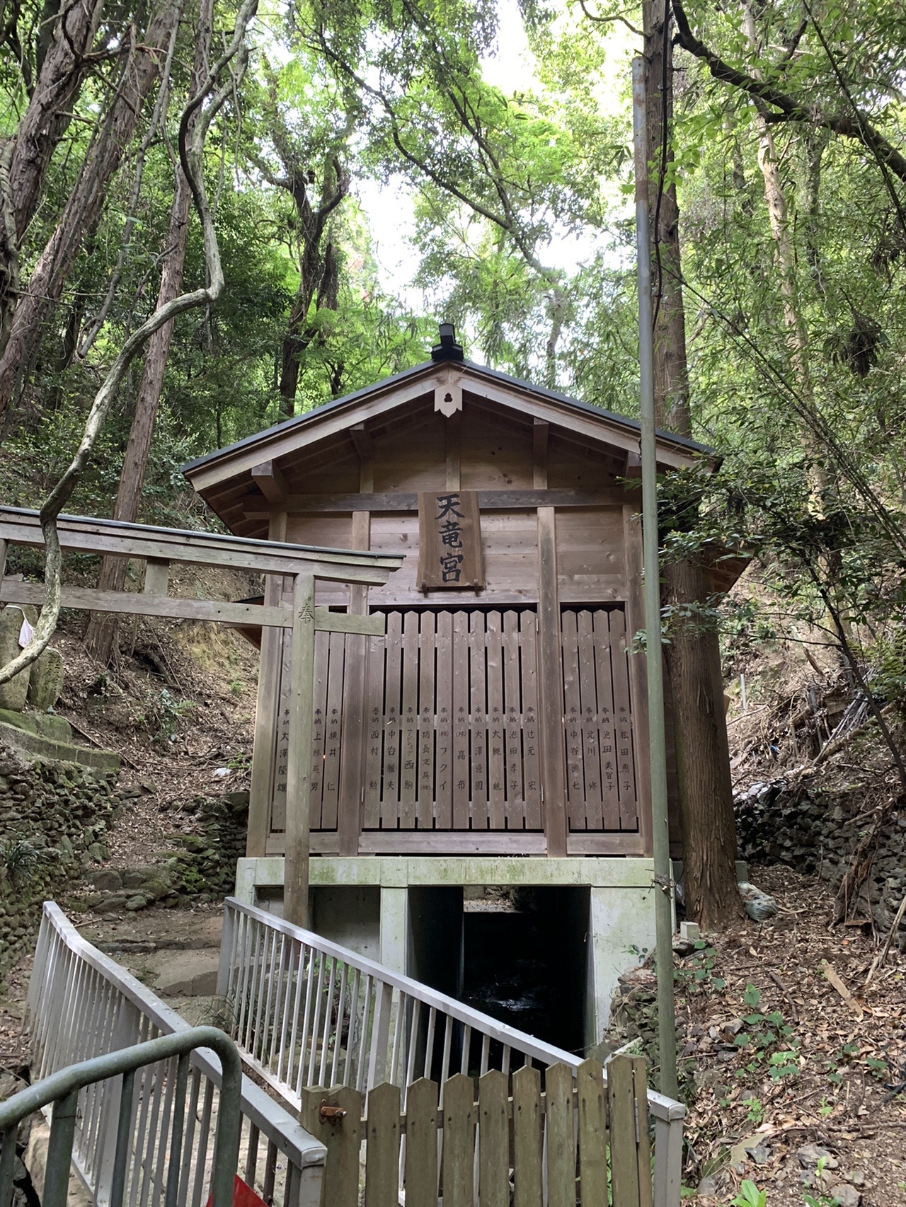 斜面に建てられた小さな木造の社。手すりのついた階段が下から続いている