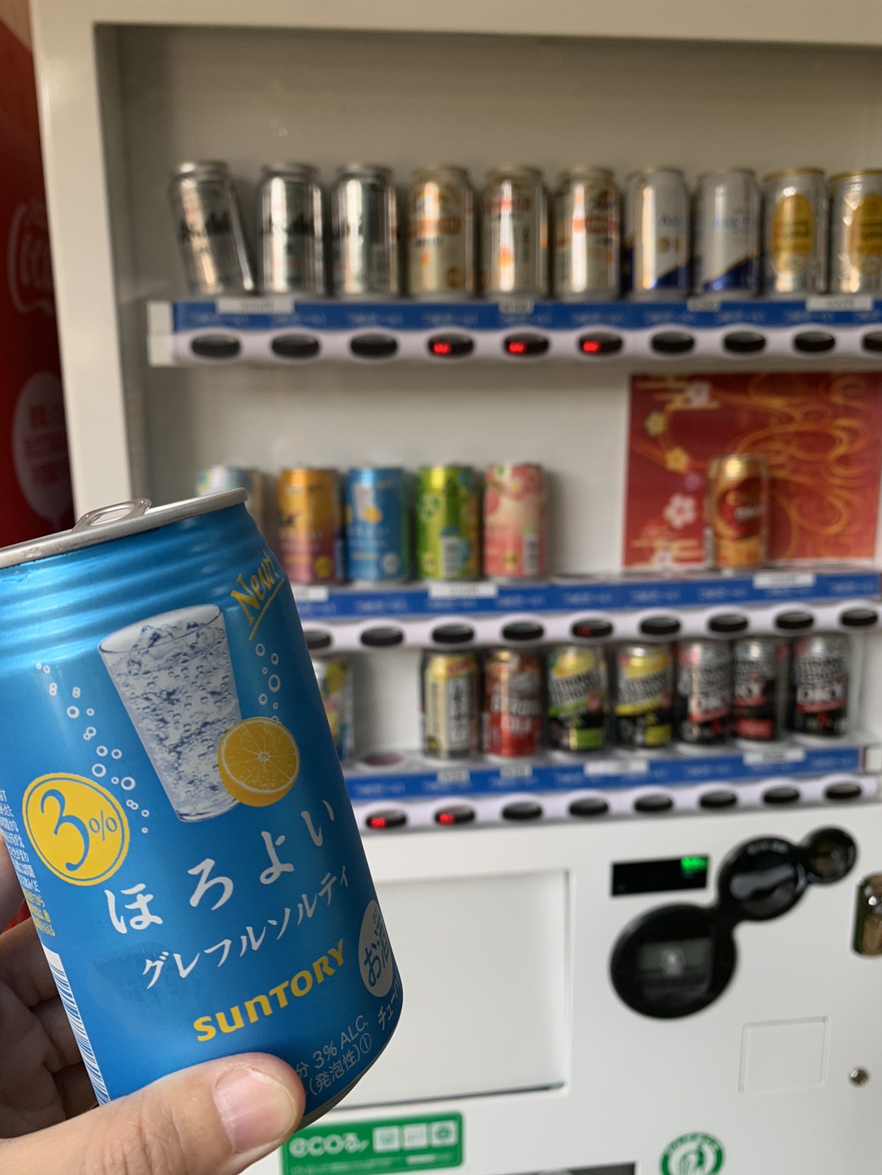 自動販売機の前で手に持たれた、缶チューハイの缶