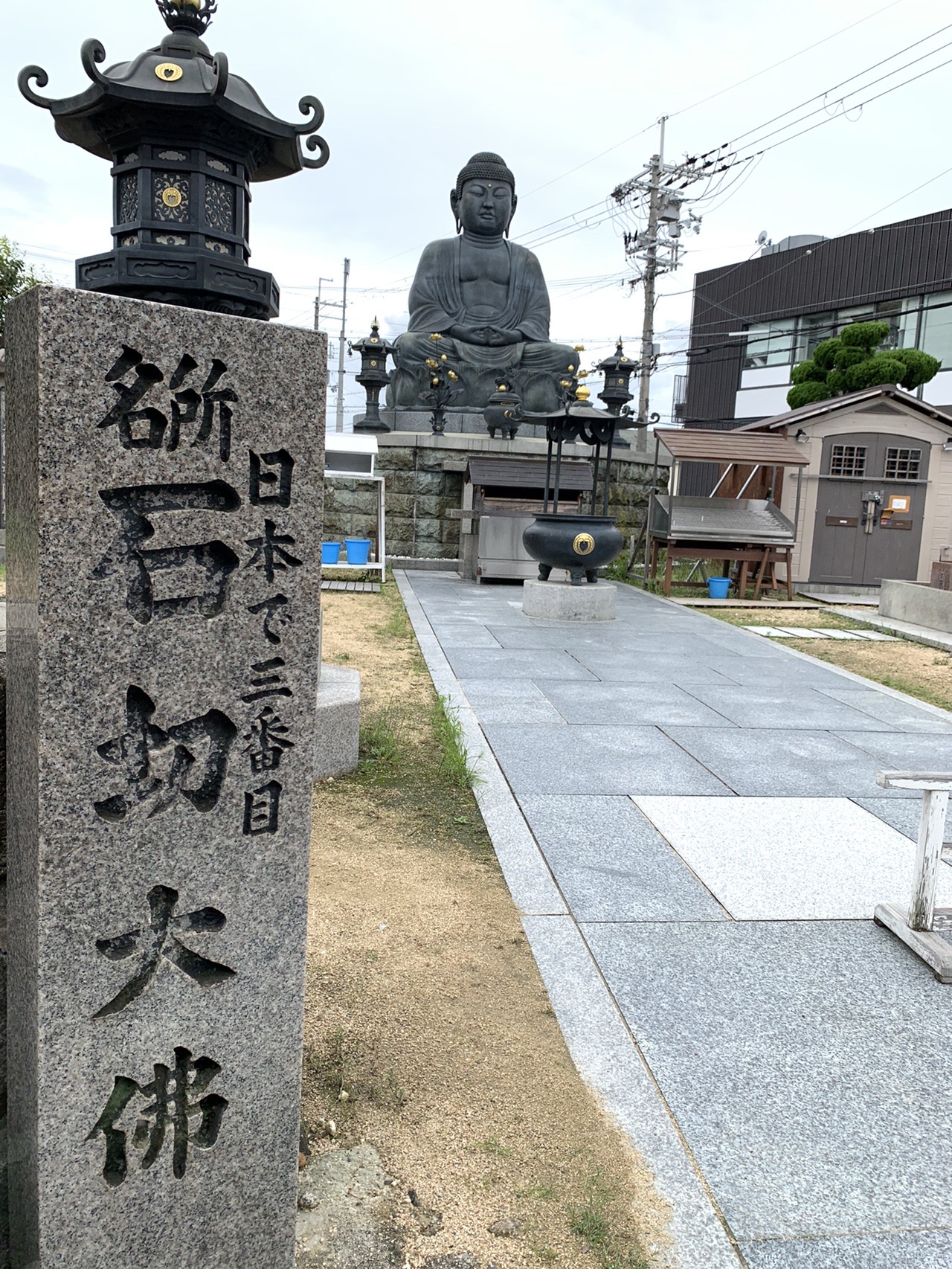 「日本三番目 石切大佛」と刻まれた石柱と、その奥に座る大仏