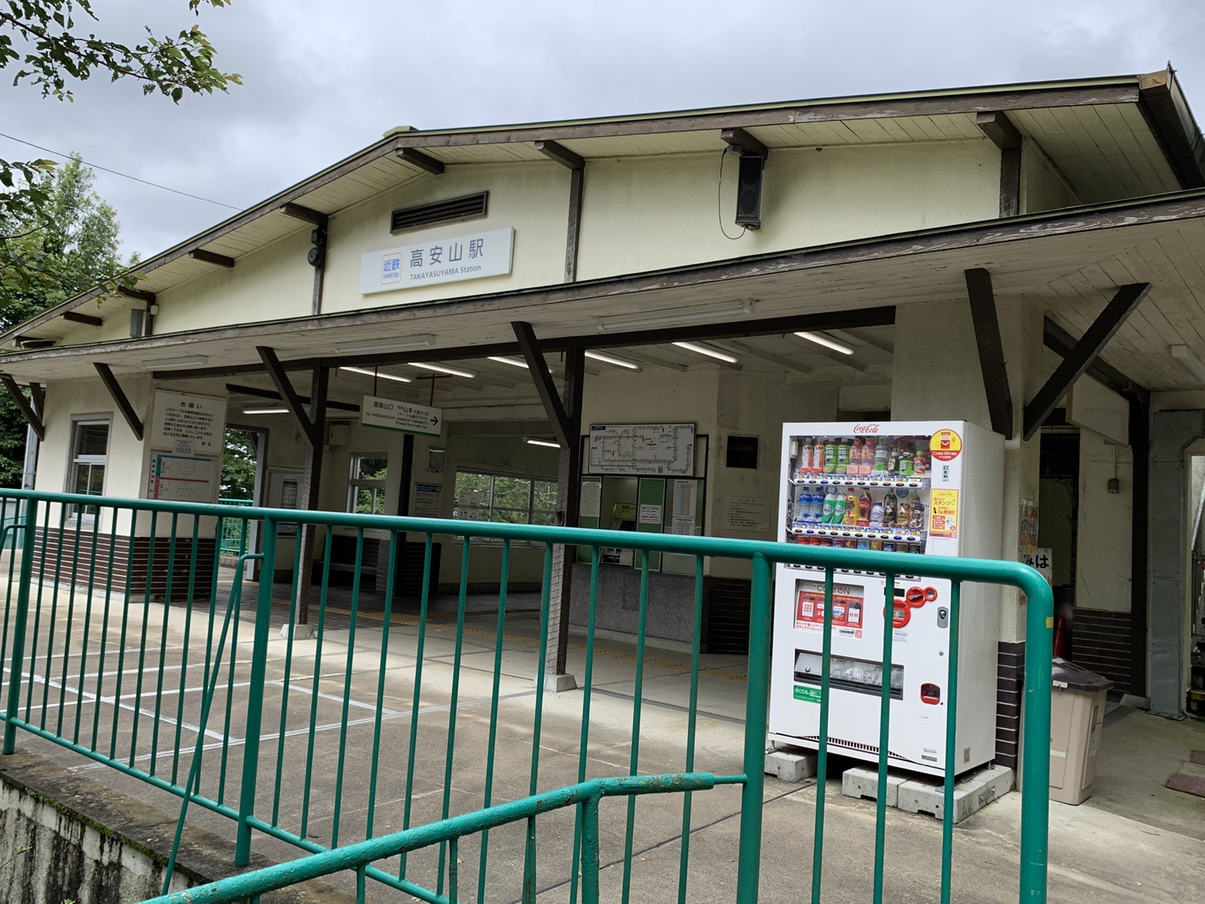 山の上にある小ぶりな駅舎。「高安山駅」の駅名標と自動販売機が見える