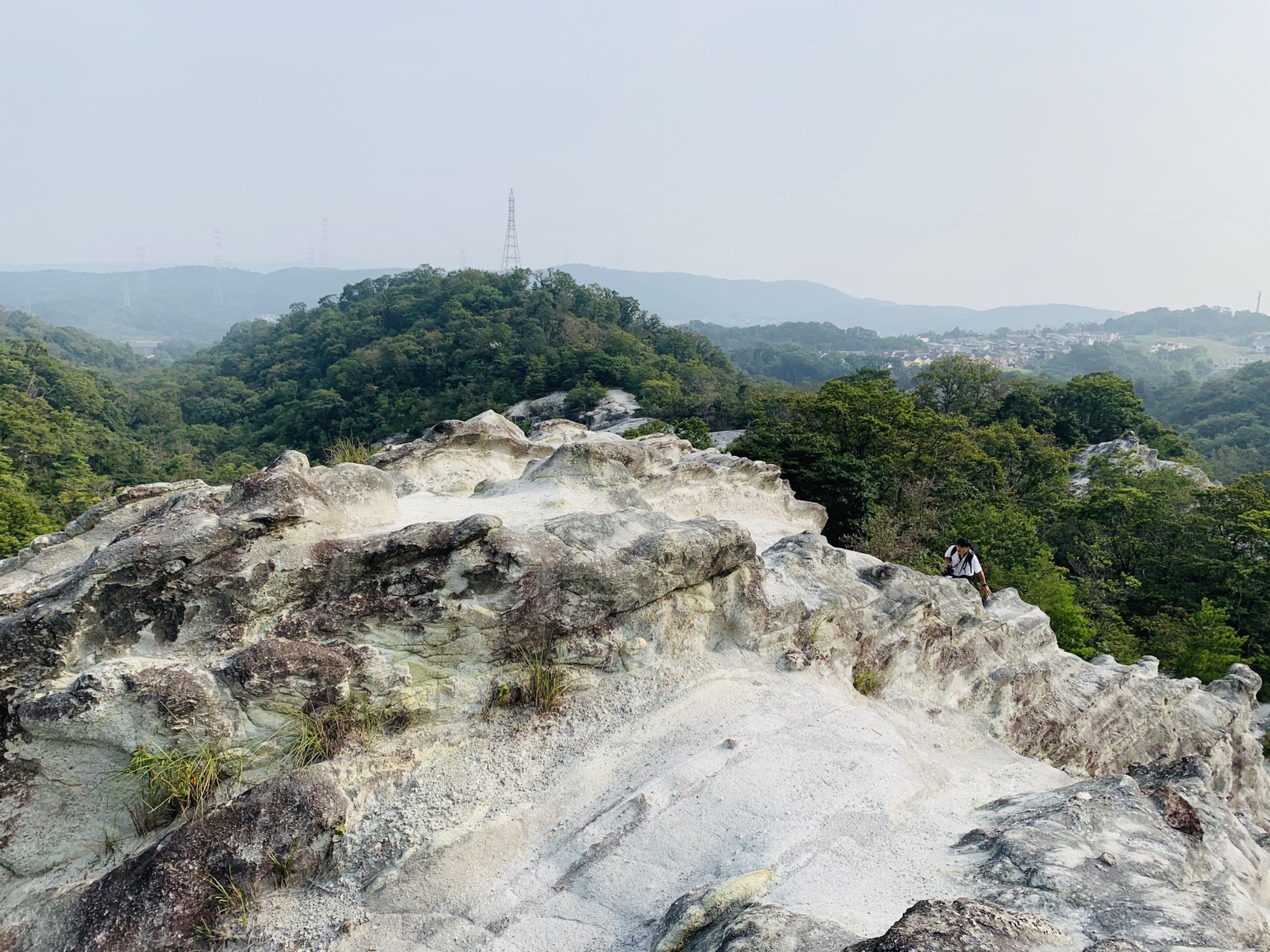 白い岩の尾根の上から見下ろす谷と、その向こうに広がる緑の山並み