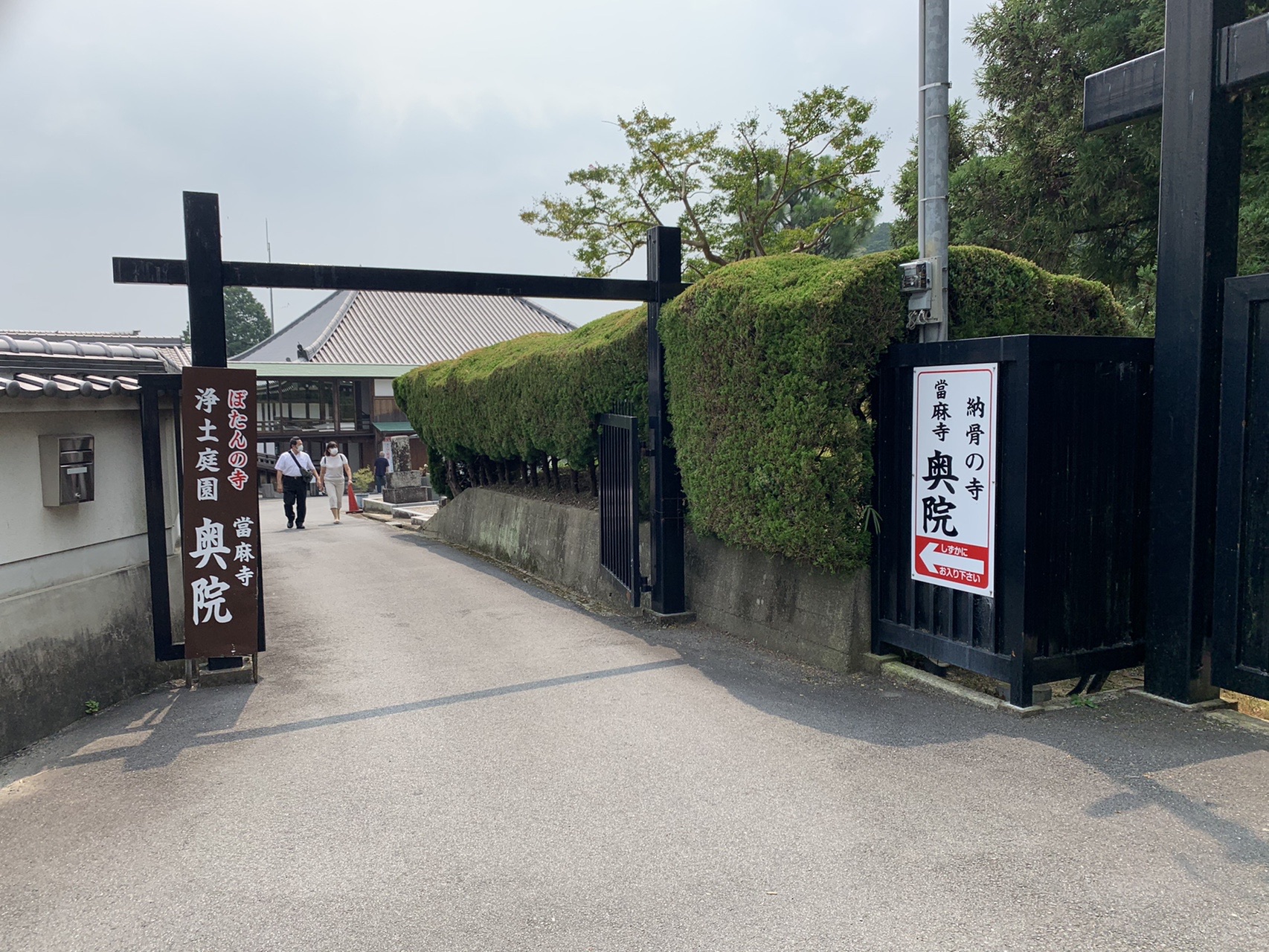 當麻寺奥院の黒い門柱と、生垣に挟まれた参道