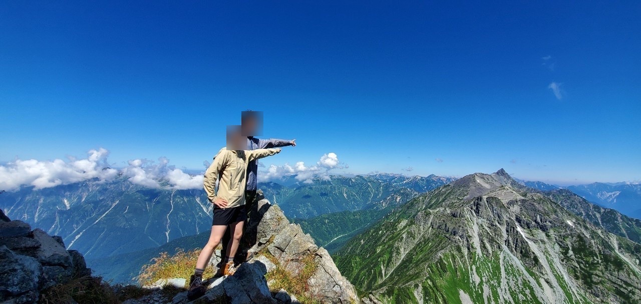 岩の上に立ち、雲海の向こうの山並みを指さす2人。プライバシー保護のため顔にぼかしを入れています