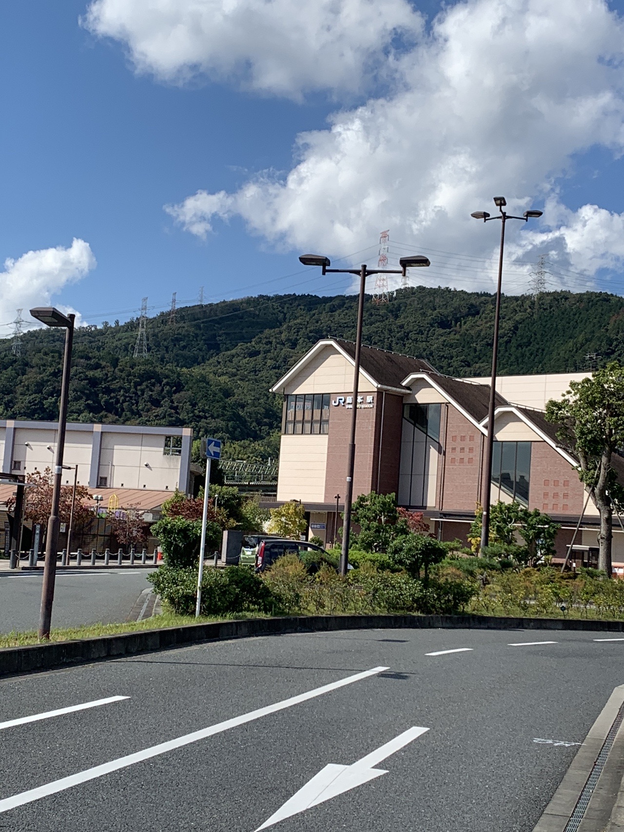 広い道路の先に見える島本駅の駅舎と、その向こうに続く山並み