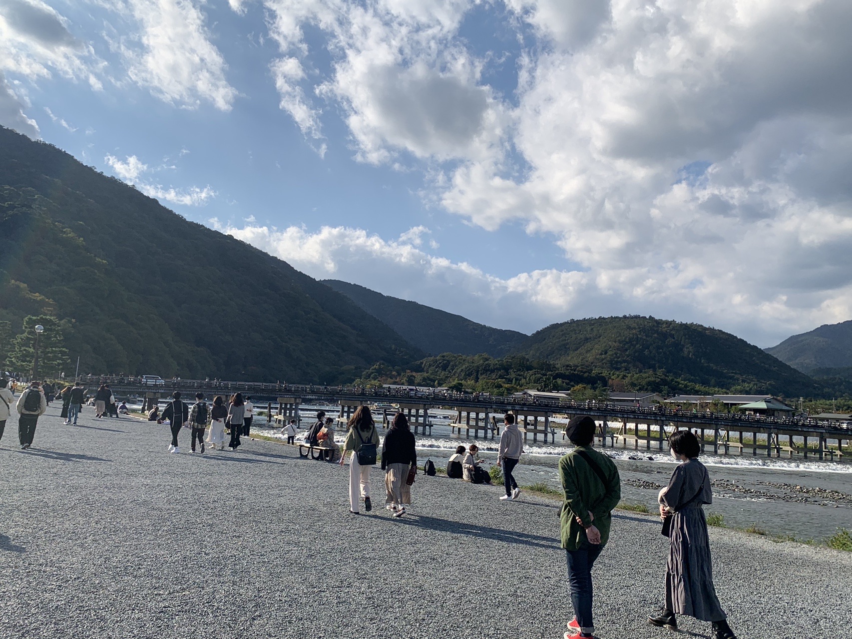 桂川の河原越しに見える渡月橋と、河原を歩く多くの人