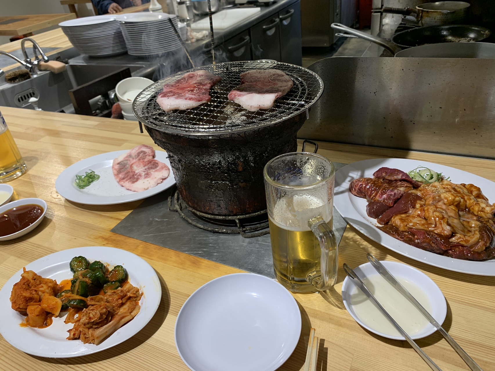 七輪の上で焼かれている牛肉と、ビール、キムチなどが並んだテーブル
