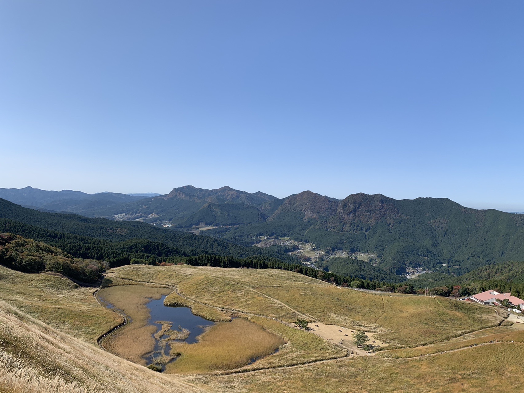 峠の上から見下ろすお亀池と集落、その向こうの山並み