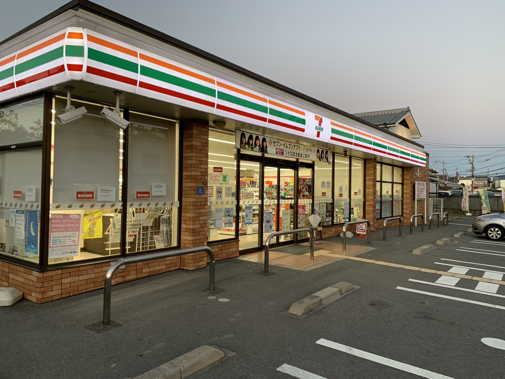 夕方のコンビニエンスストアの店舗と駐車場
