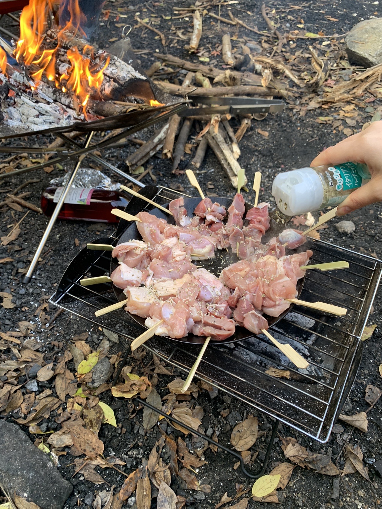 網の上に並べた焼き鳥の串に塩を振っているところ