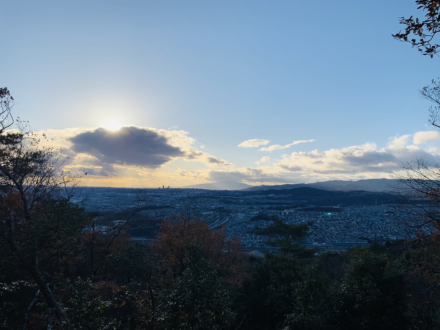夕方の空。雲の間から光が差し、下に街が広がる