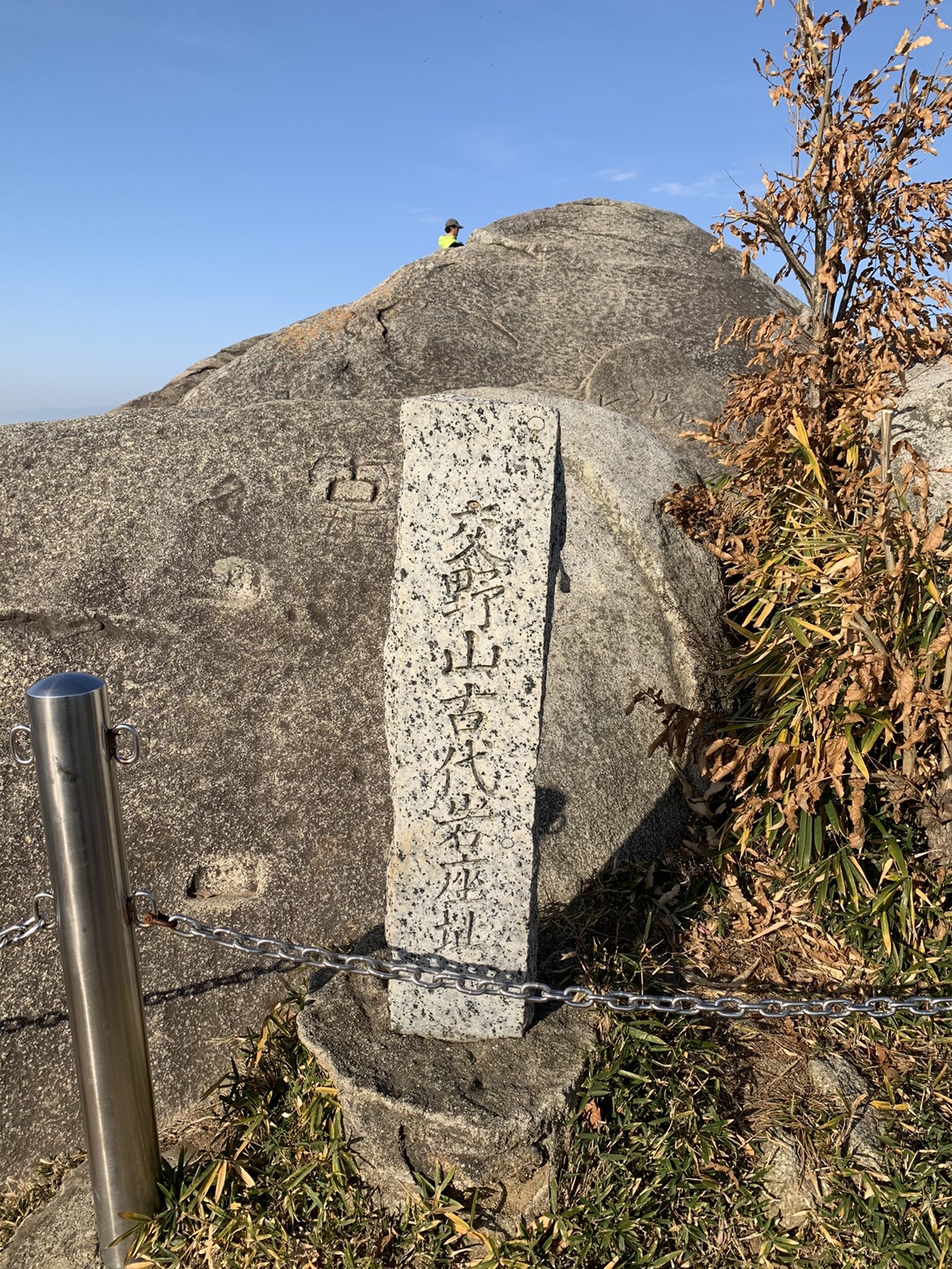 交野山の山頂にそびえる巨大な岩と、その前に立つ石碑