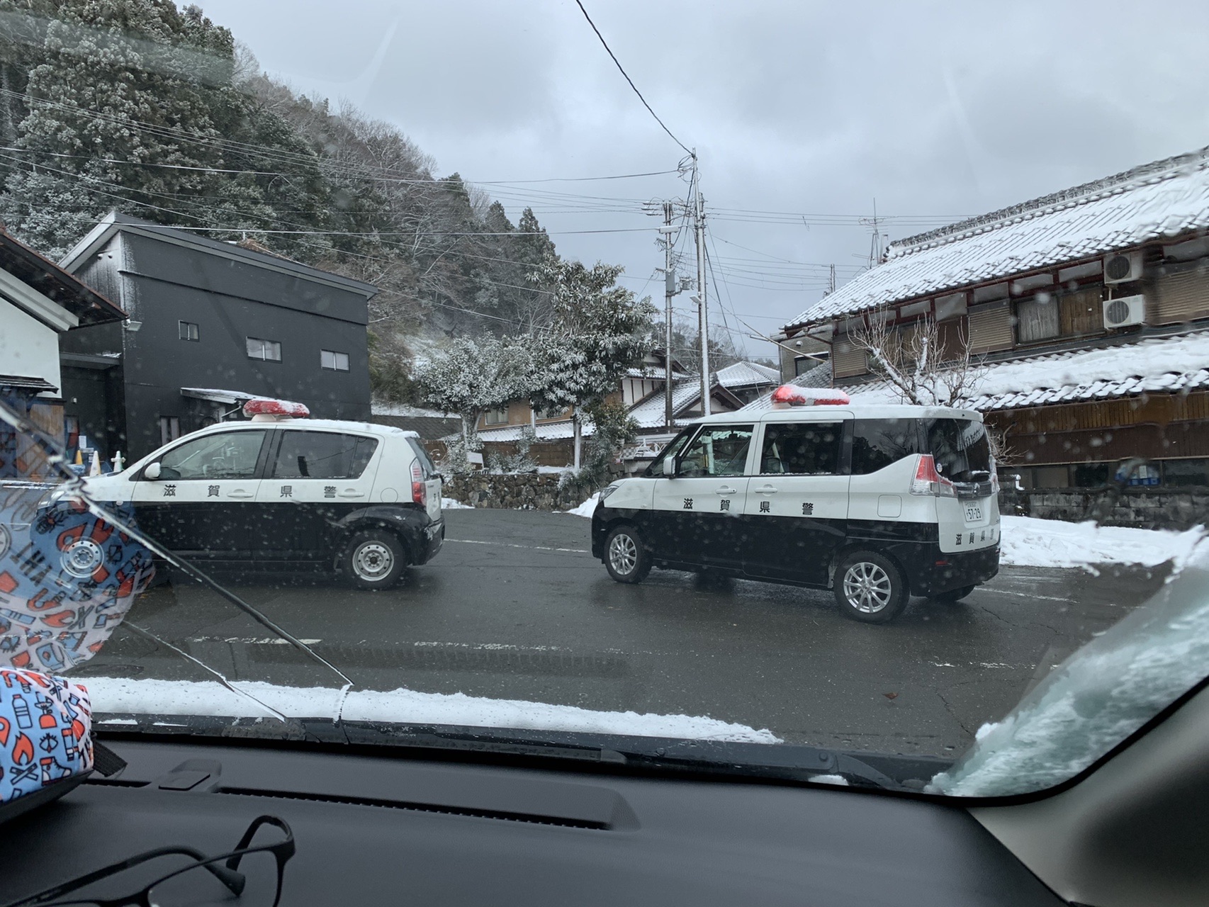 雪の駐車場に並ぶ車。フロントガラス越しの風景