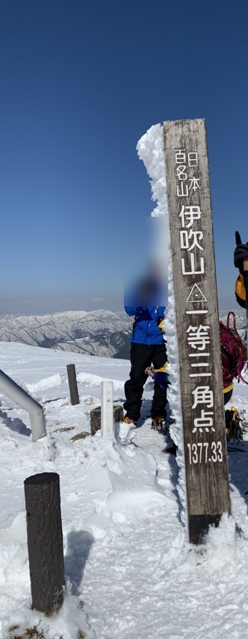 「日本百名山 伊吹山 一等三角点 1377.33」と書かれた雪まみれの標柱