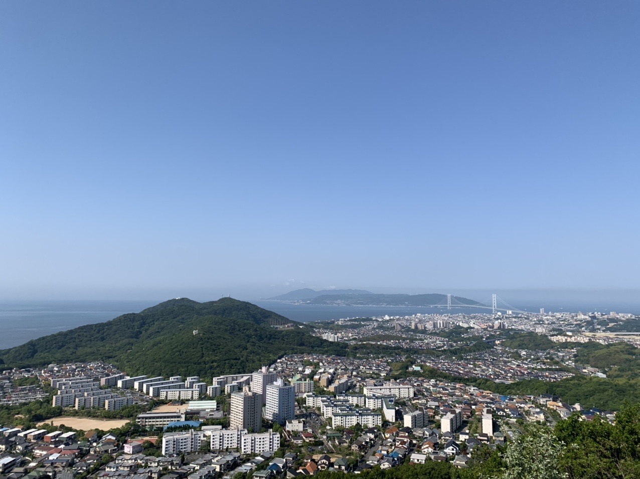 栂尾山から見下ろす神戸の住宅地と、その向こうの海と山