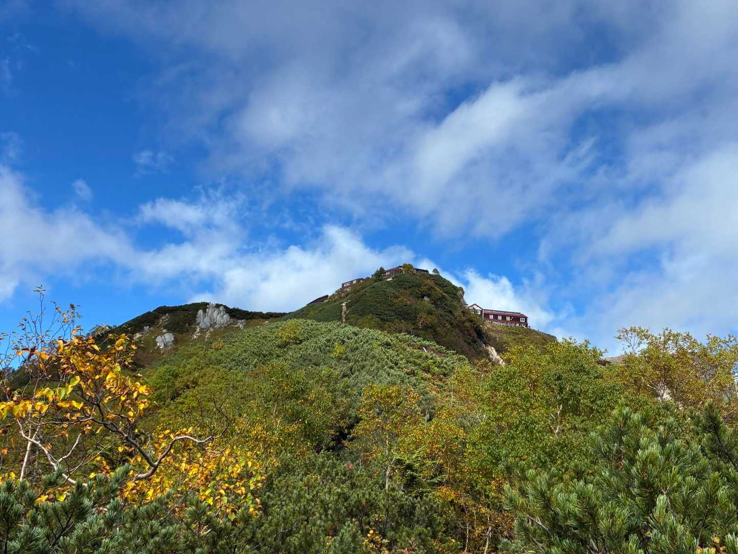 稜線の上に小さく見える燕山荘の建物。手前の斜面は紅葉が始まっている