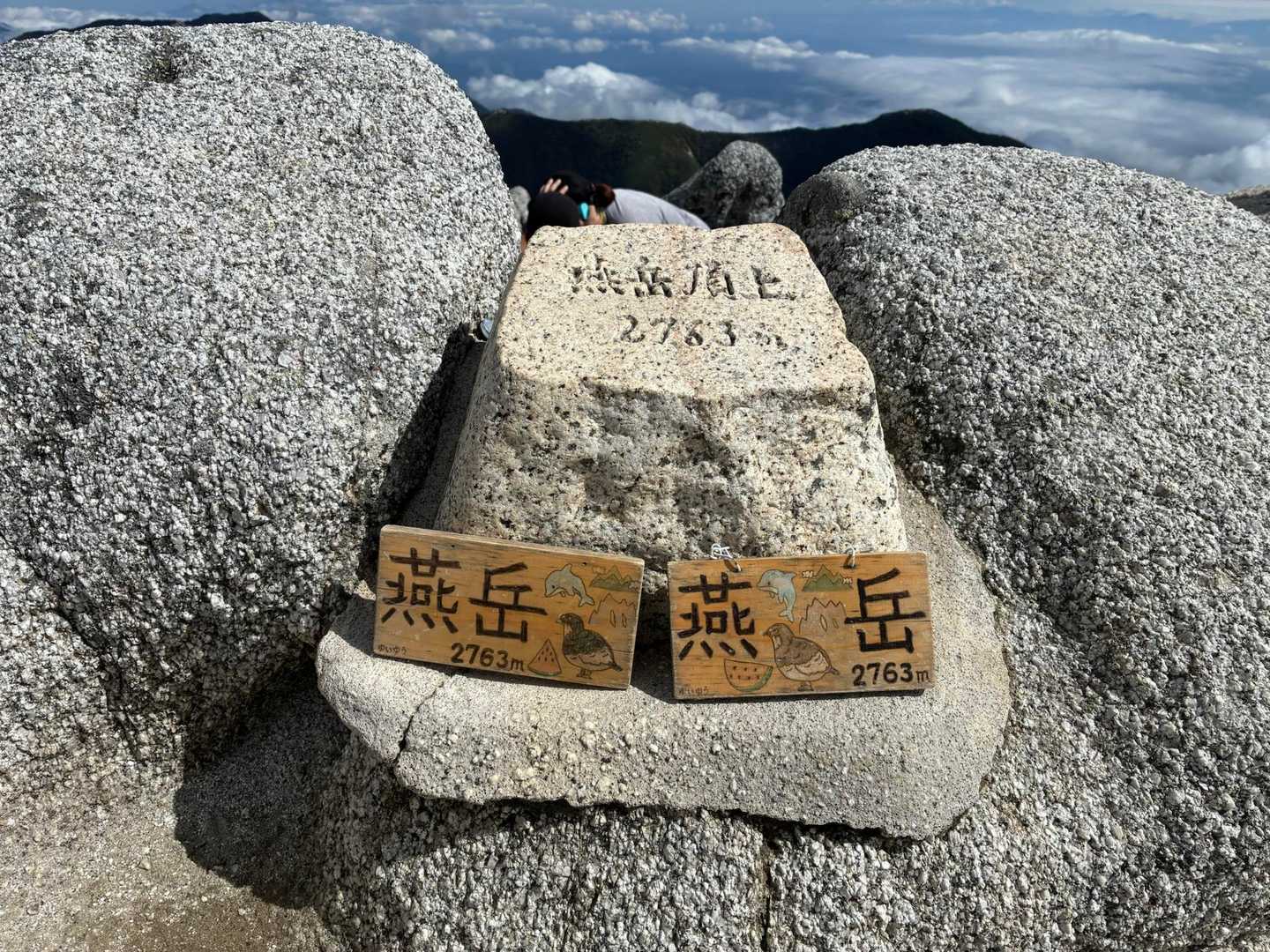 燕岳山頂の石積みに置かれた木製の山名標。「燕岳」と書かれている